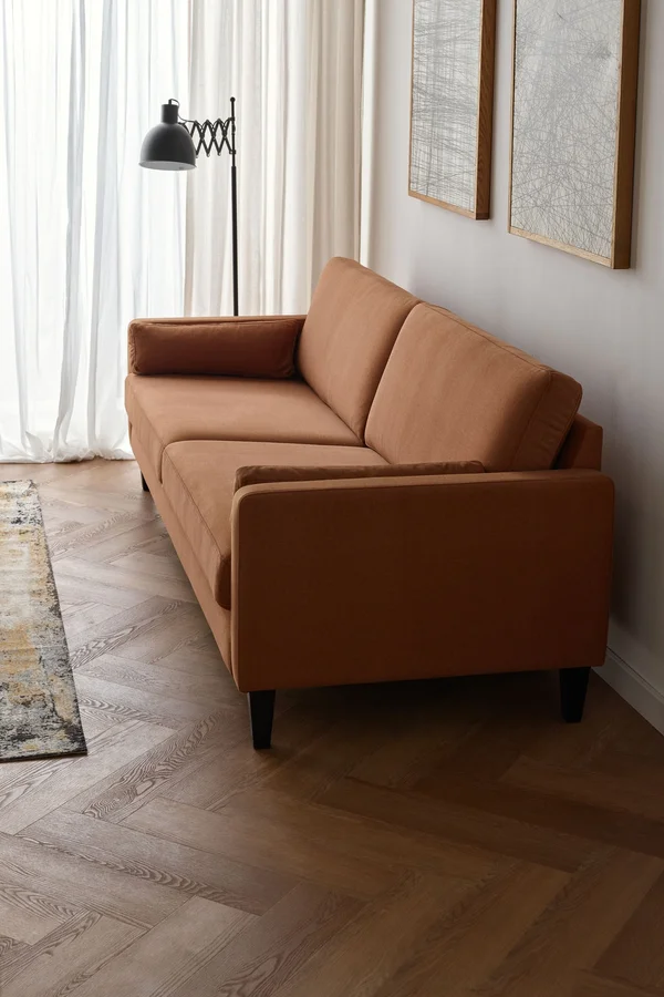 Ruda sofa na tle jasnej ściany
